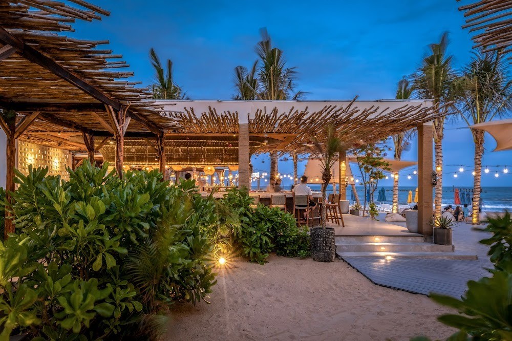 Khung cảnh Aloha Beach Club với ánh đèn vàng và band acoustic bên hồ bơi
